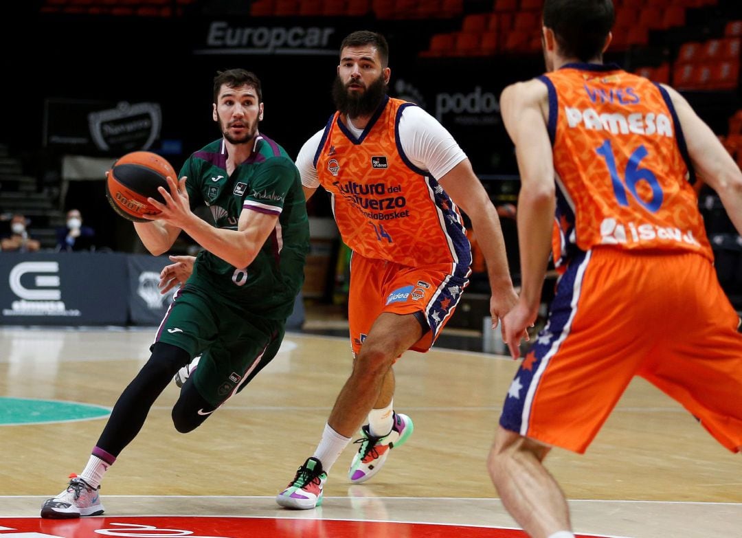 El pívot del Valencia Basket, Bojan Dubljevic (c), trata de frenar el avance del escolta del Unicaja, Dario Brizuela, durante el partido de la quinta jornada de la Liga Endesa que han disputado este domingo en la Fonteta. 