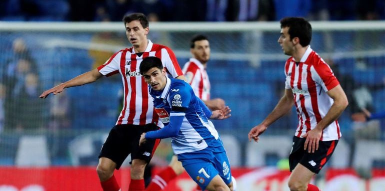 El delantero del Espanyol Gerard Moreno (c) pelea un balón con los jugadores del Athletic Ander Iturraspe (i) e Iñigo Lekue (d) durante el partido de liga correspondiente a la decimonovena jornada disputado en el RCD stadium