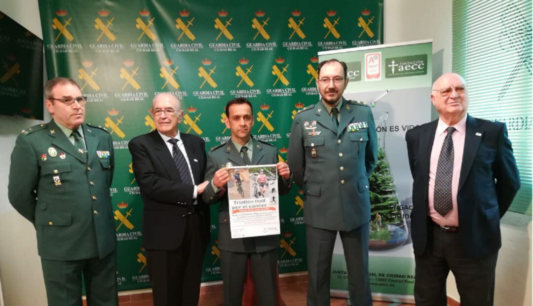 Emeterio Flox Hernández, con el cartel, junto al Tte Coronel, Juan Antonio Valle Gómez y al presidente de la Asociación Contra el Cáncer, Félix Peinado entre otros miembros.