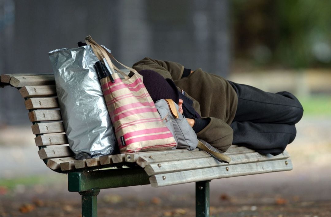 Persona sin hogar descansa en un banco de la calle en una imagen de archivo