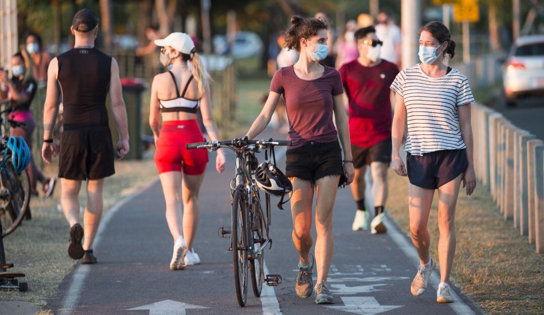 Varias personas caminan con mascarilla.