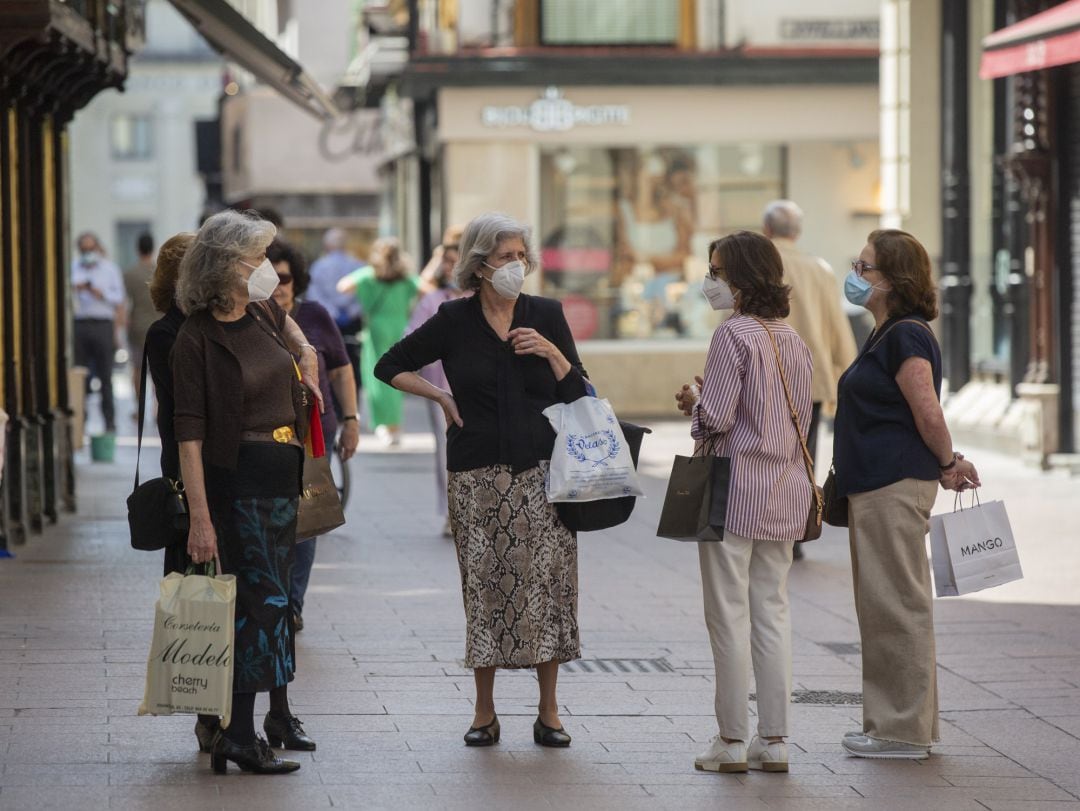 Varias personas protegidas con mascarillas conversan en una calle del centro de Sevilla.