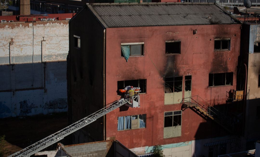 Los bomberos en la nave okupada donde se produjo el incendio, en Badalona.