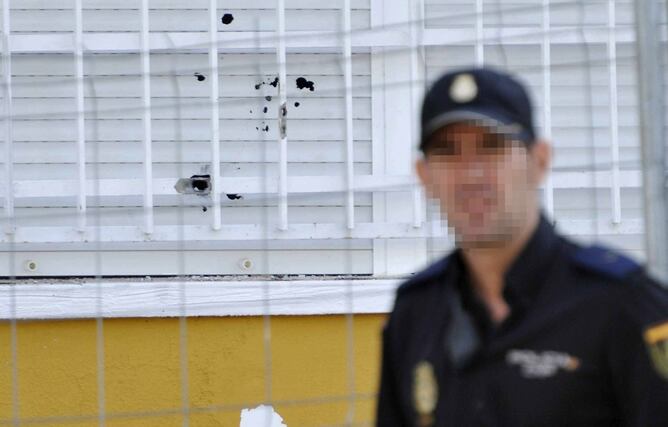 Un policía pasa por delante de una de las persianas llenas de orificios de bala en el edificio donde una niña de 7 años ha muerto