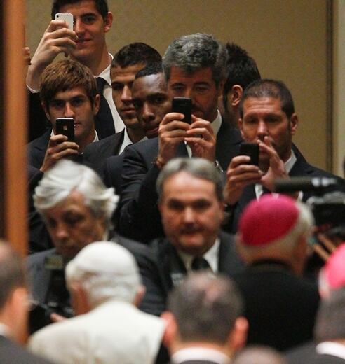 El consejero delegado del Atlético, Miguel Ángel Gil, el entrenador Diego Simeone y algunos jugadores fotografían con sus móviles al Papa antes de la recepción a la plantilla rojiblanca que ha tenido lugar en el Vaticano.