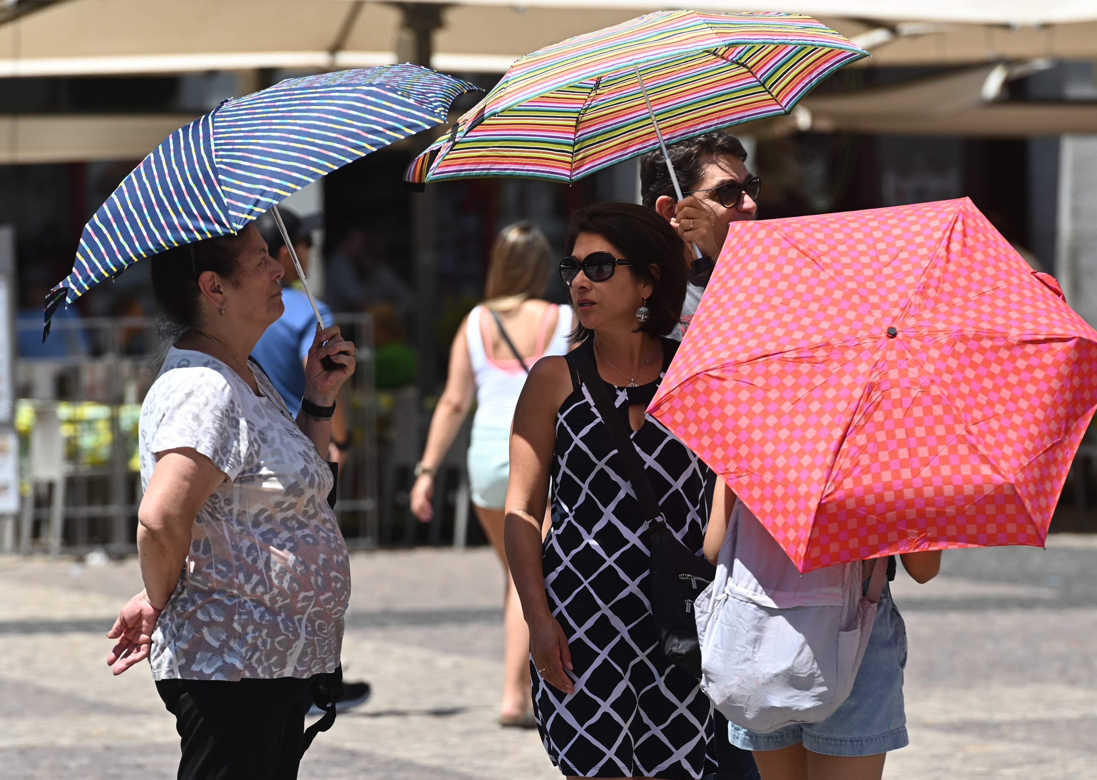 Varias personas pasean con una sombrilla por el centro de Madrid