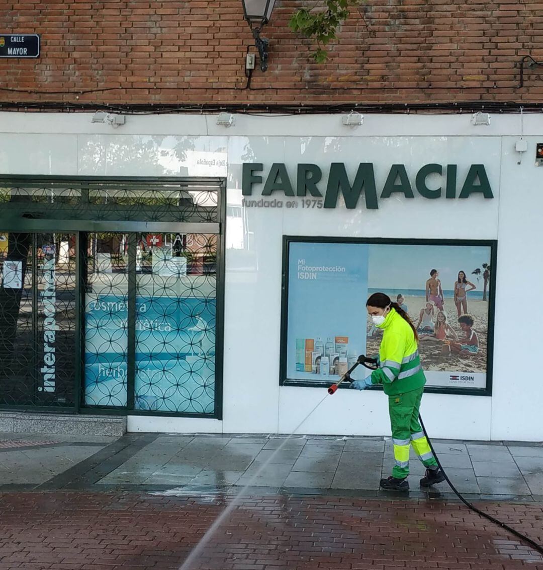 Trabajadora de la Empresa de Servicios de Alcorcón (ESMASA) desinfectando la entrada a una farmacia