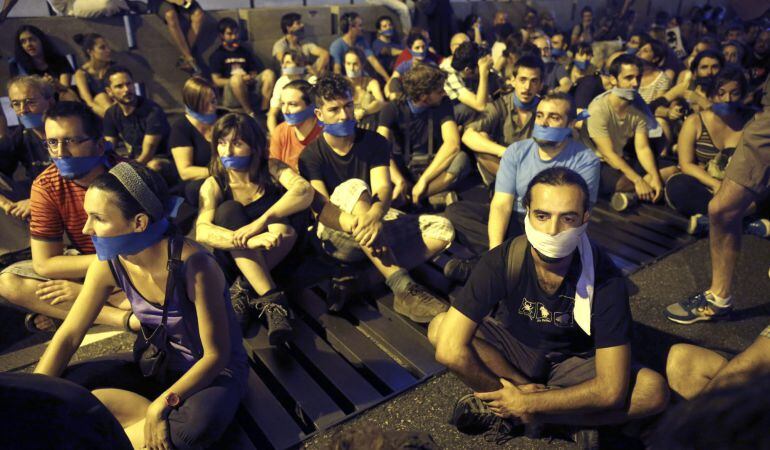 Manifestantes ante el Congreso de los Diputados, en Madrid, que han convocado a una sentada con la boca tapada en protesta por la entrada en vigor de la Ley de Seguridad Ciudadana y la reforma del Código Penal.