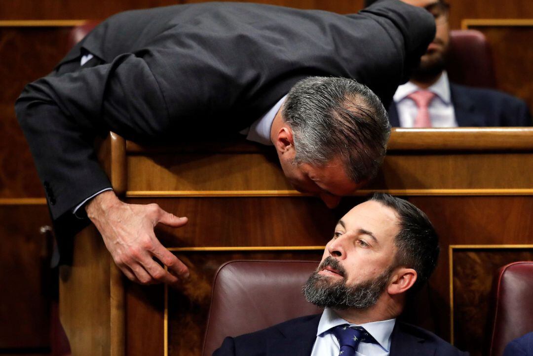 El presidente de Vox, Santiago Abascal, escucha a su compañero de grupo, Javier Ortega Smith (i), en el Congreso de los Diputados en la primera jornada de la sesión de investidura de Pedro Sánchez como presidente del Gobierno.