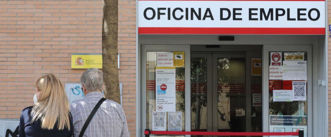 Dos personas sentadas frente a una oficina del SEPE, el día en el que se han conocido los datos de paro de mayo, a 2 de junio de 2021, en Madrid 