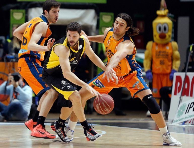 GRA174. VALENCIA, 03/01/2015.- El escolta italiano del Iberostar Tenerife Nicolás Richotti (c) intenta superar la defensa del base Guillem Vives (i) y el pívot croata Kresimir Loncar (d), del Valencia Basket, durante el partido de la decimoquinta jornada de la Liga ACB que se juega hoy en el Pabellón de la Fuente de San Luis de Valencia. EFE/Juan Carlos Cárdenas