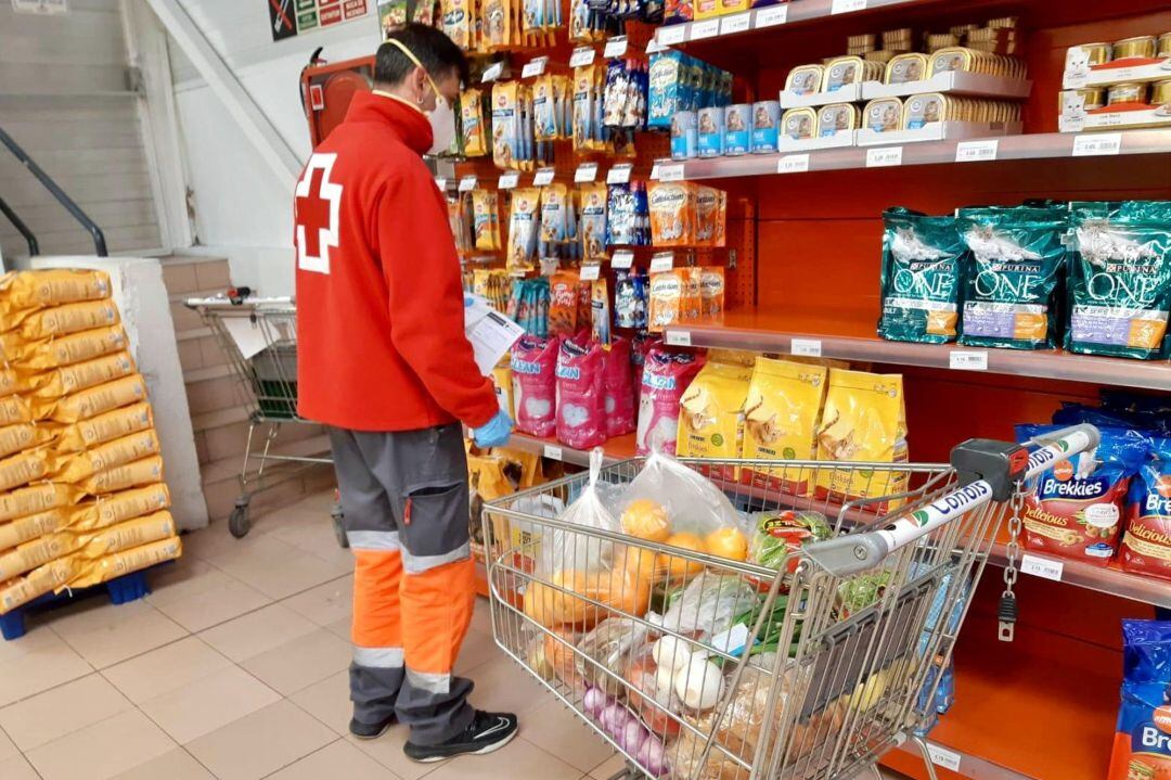 Un voluntari de la Creu Roja fent la compra per a un usuari de l&#039;entitat en un supermercat