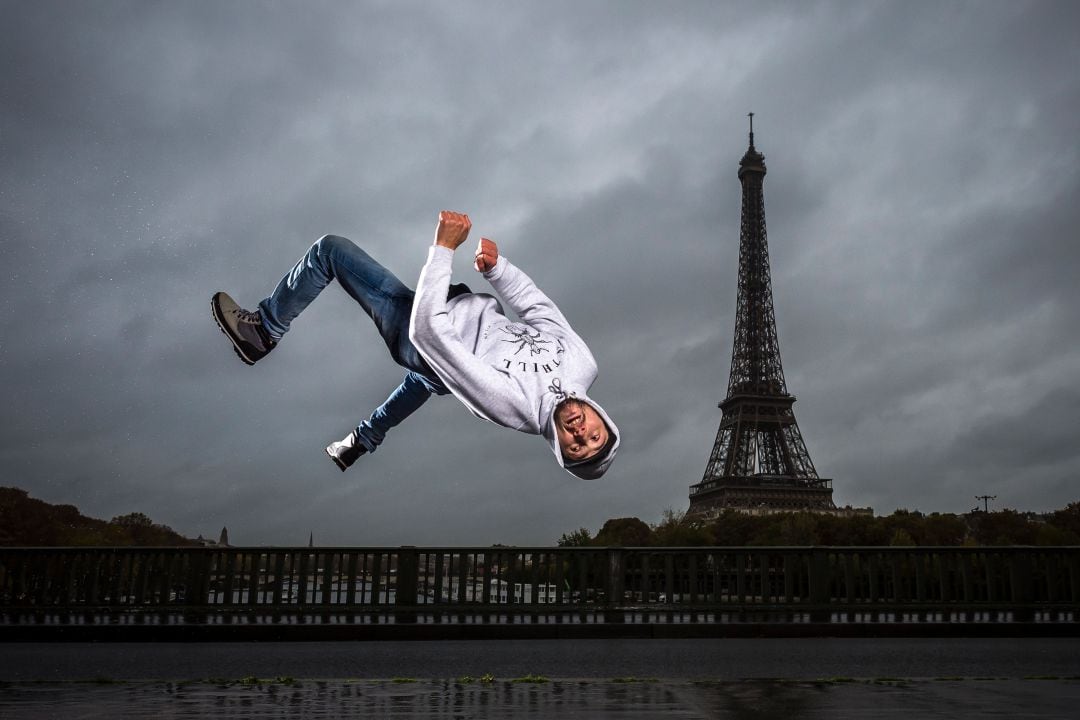 Un hombre practica breakdance con la torre Eiffel de fondo