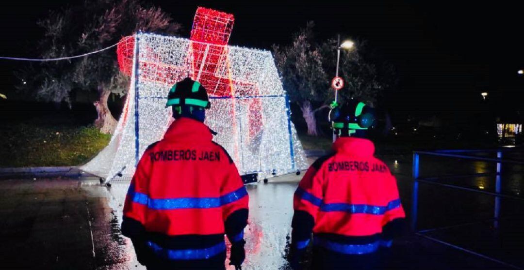 Dos bomberos frente a uno de los adornos navideños que ha resultado afectado por el temporal.