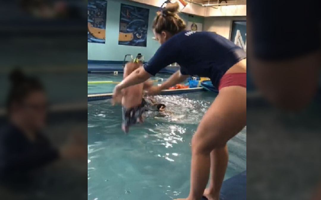 La instructora tirando al pequeño al agua.