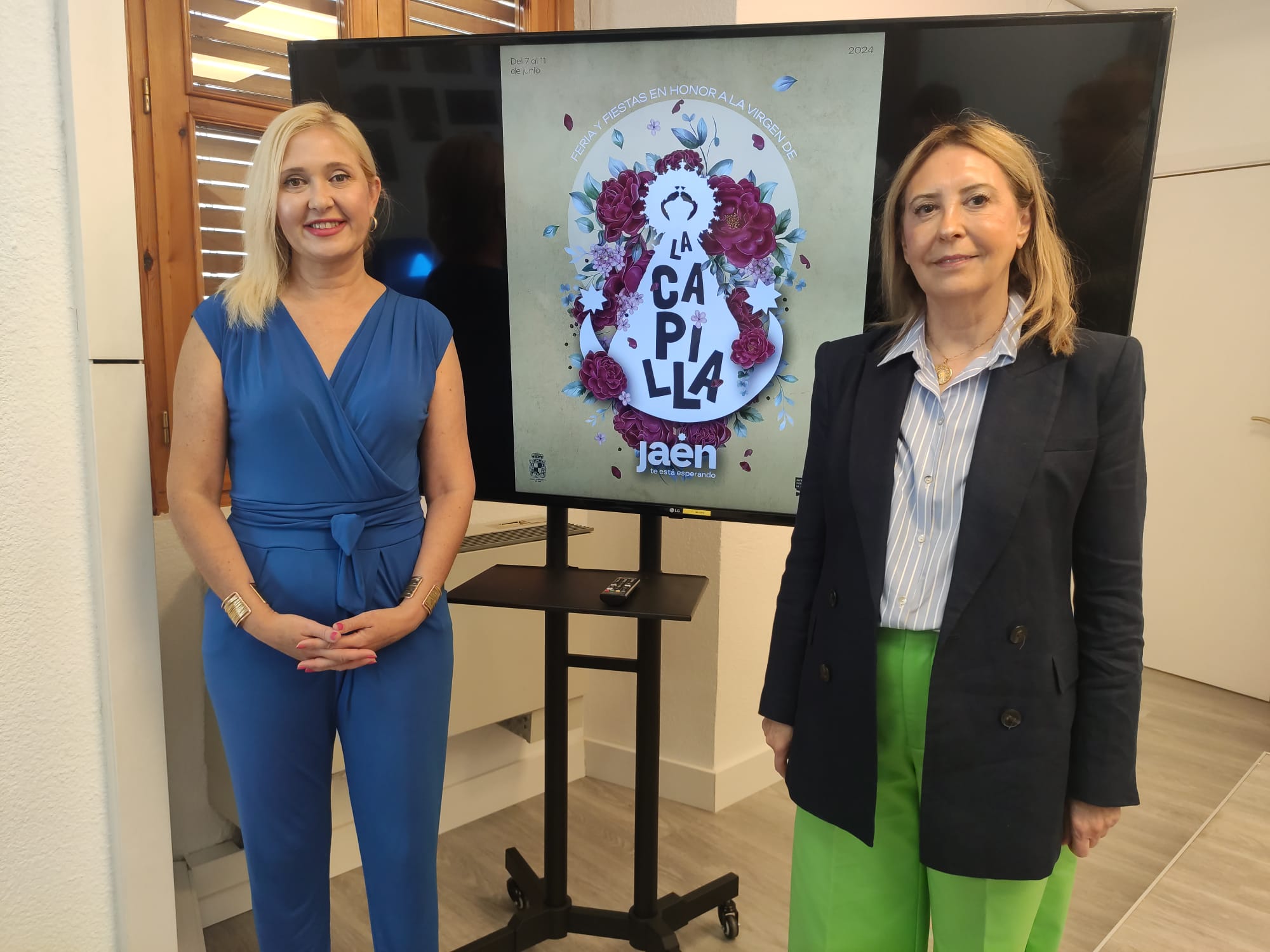 La concejala de Cultura, Turismo, Festejos, Juventud y Patrimonio Histórico de Jaén, María Espejo, y Úrsula Colmenero, hermana mayor de la Cofradía de la Virgen Capilla, ante el cartel de la Feria de junio de este año.