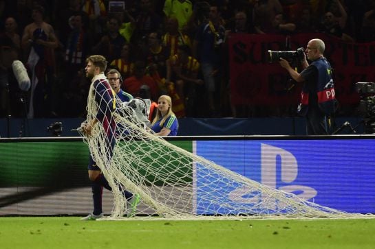 Barcelona&#039;s defender Gerard Pique has wrapped himself in the cut goal net after the UEFA Champions League Final football match between Juventus and FC Barcelona at the Olympic Stadium in Berlin on June 6, 2015. FC Barcelona won the match 1-3. AFP PHOTO / 