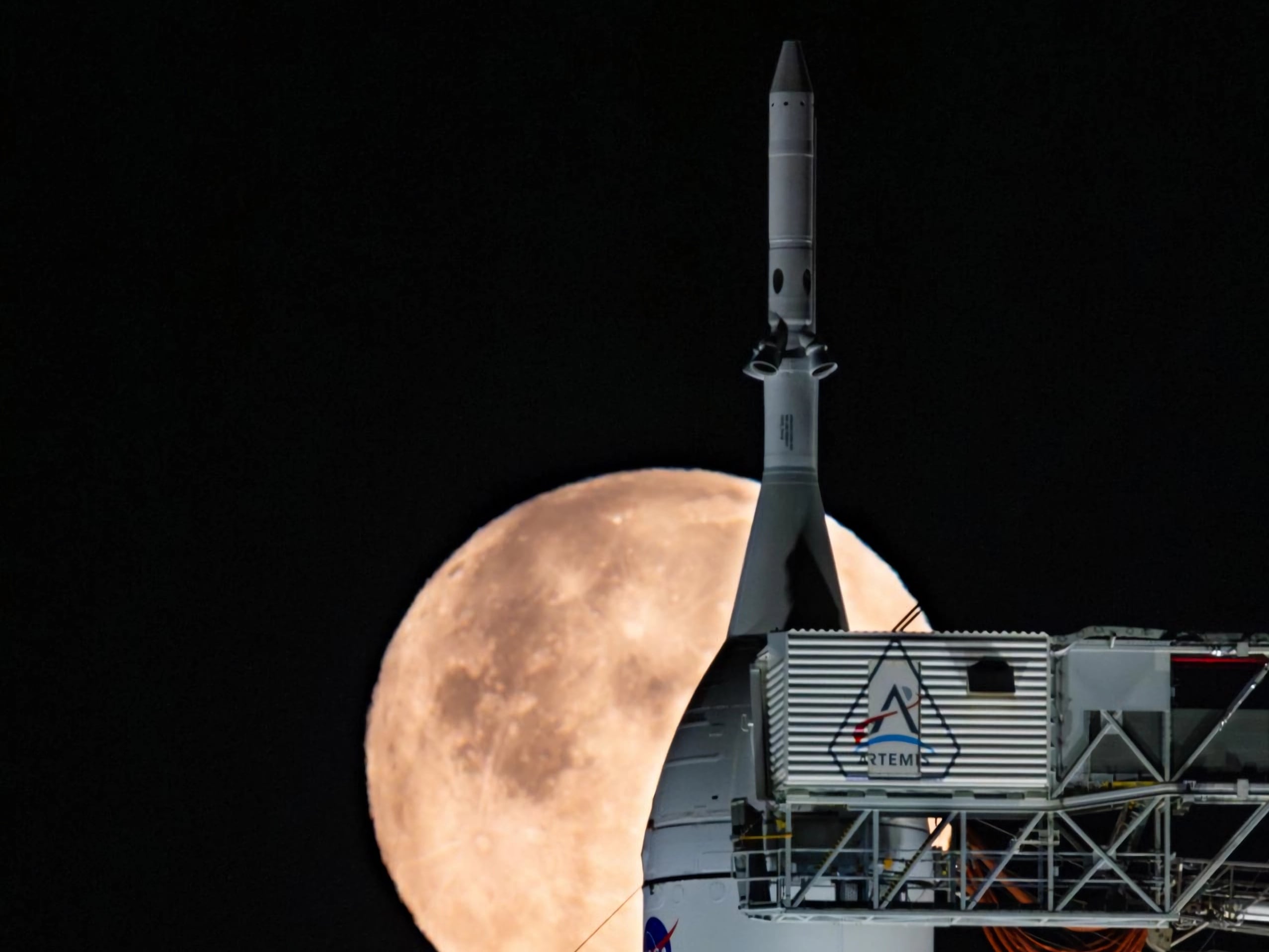 Fotografía del 1 de febrero de 2026 cedida por la agencia espacial estadounidense NASA que muestra una luna llena brillando detrás del cohete del Sistema de Lanzamiento Espacial