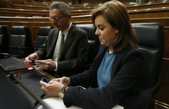 La vicepresidenta del Gobierno, Soraya Sáenz de Santamaría, y el ministro de Justicia, Alberto Ruiz Gallardón, consultan sus teléfonos móviles poco antes del inicio del debate