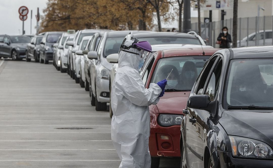 Un sanitario realiza una prueba PCR a una persona desde su vehículo 