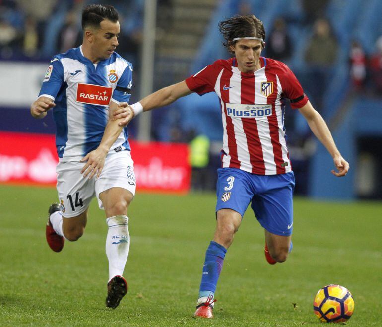 El defensa brasileño del Atlético de Madrid Filipe Luis (d) juega un balón ante José Manuel Jurado, del RCD Espanyol, durante el partido de la decimocuarta jornada de Liga en Primera División ante el Atlético de Madrid disputado esta noche en el estadio Vicente Calderón. 