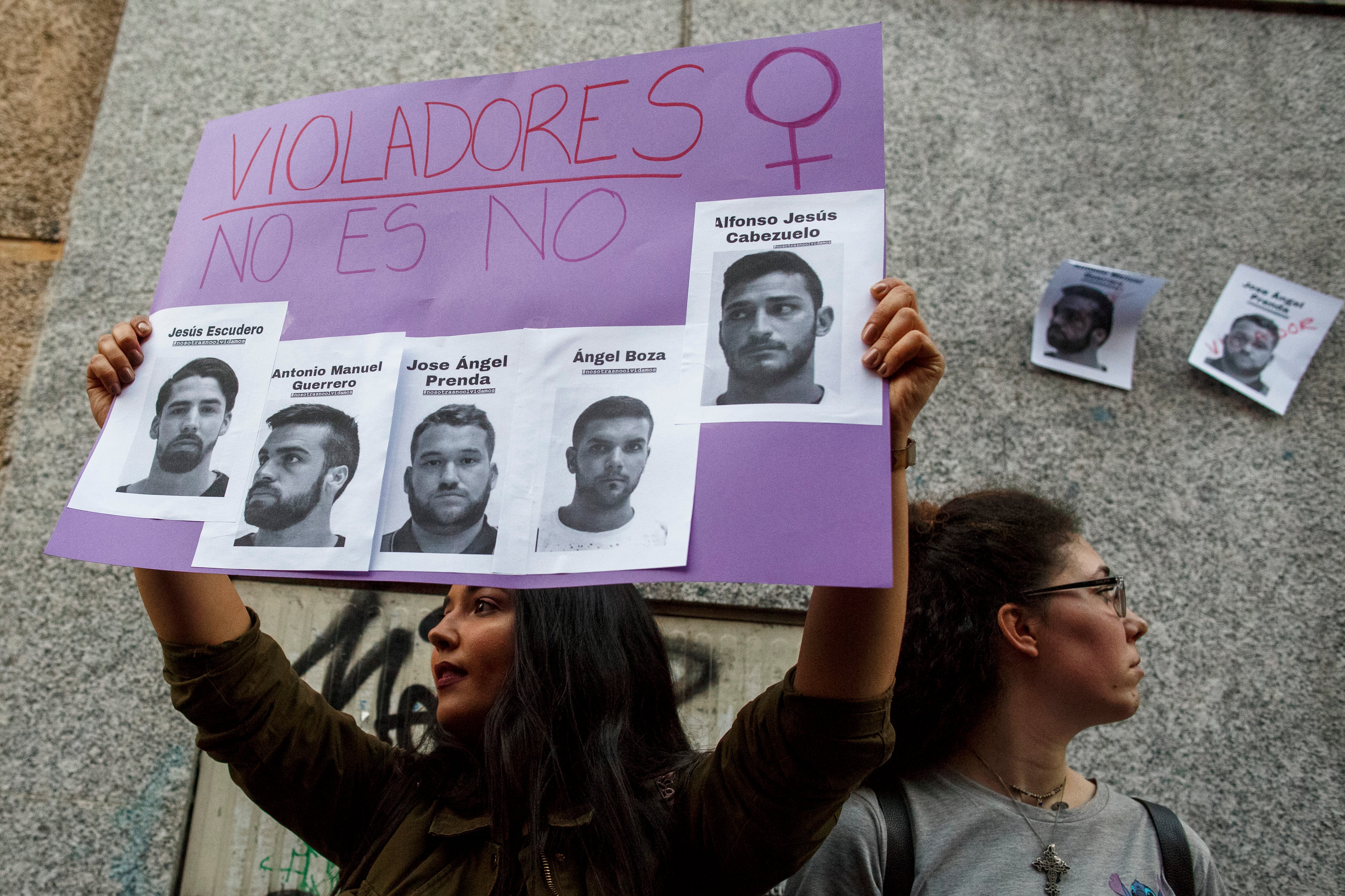 Una manifestante sostiene un cartel con fotografías de los miembros de &#039;La Manada&#039;