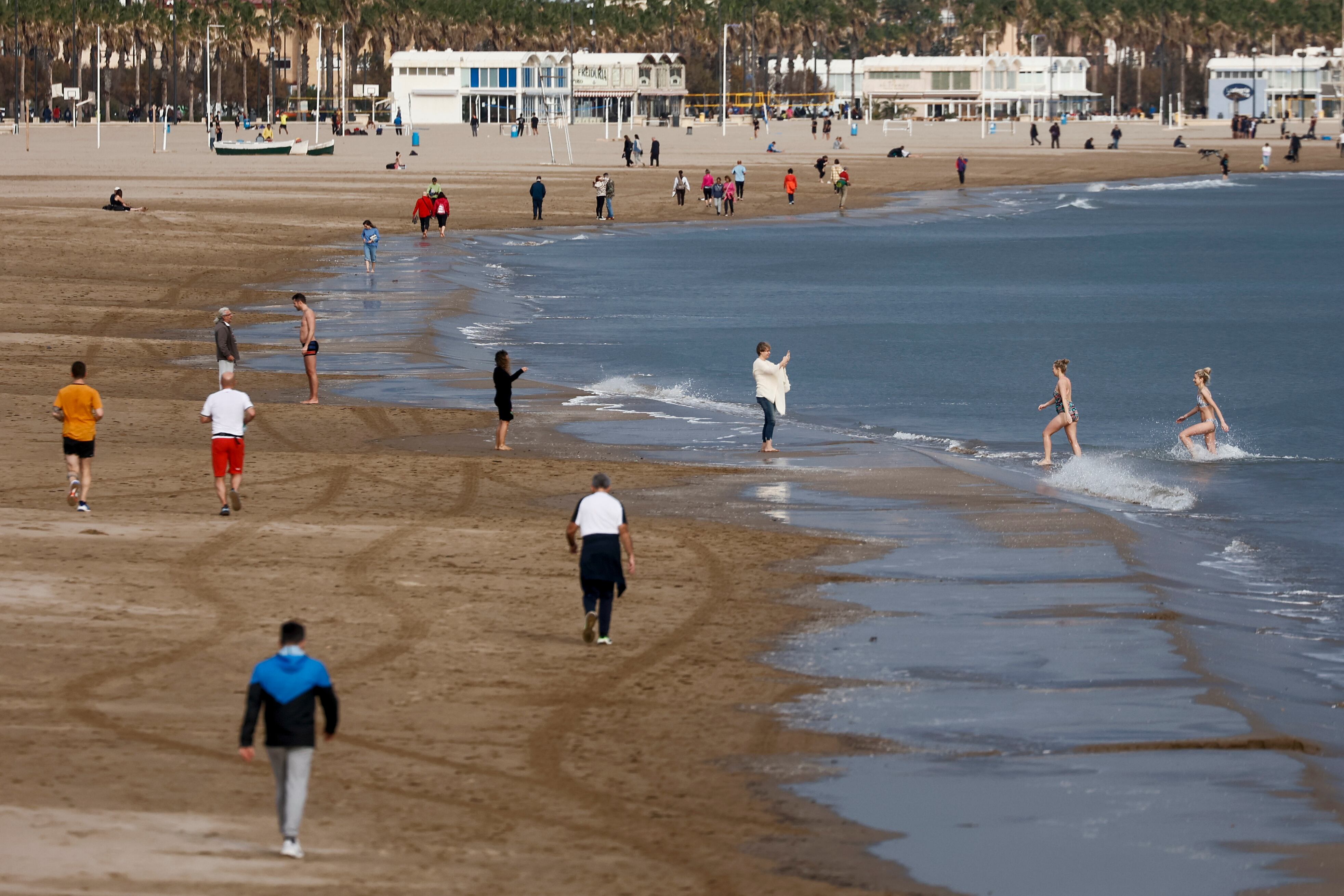 Varias personas disfrutan del buen tiempo en la playa de la Malvarrosa.