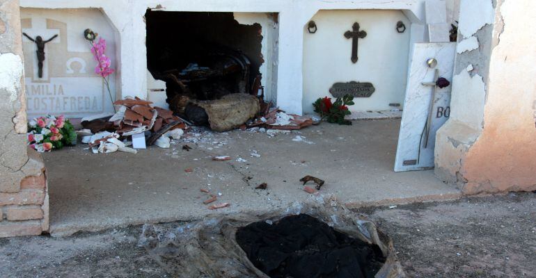 Pla general d'una de les tombes profanades del cementiri de Castelldans amb les restes del difunt a l'exterior i tota la tàpia trencada, el 4 de maig de 2016.