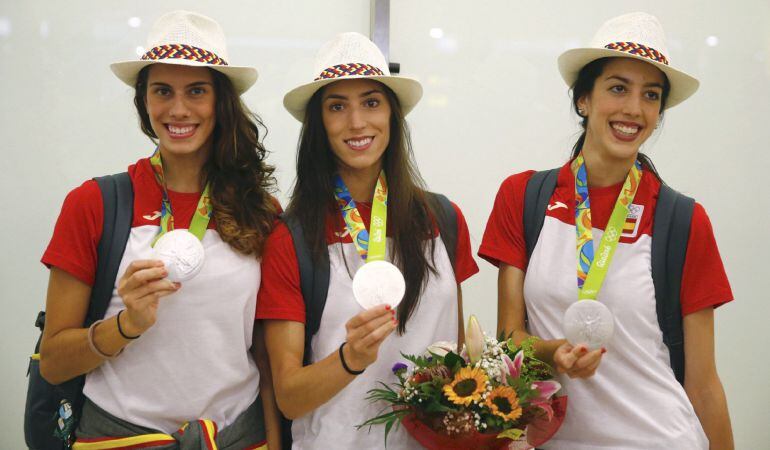 Las gimnastas Lourdes Mohedano (i), Sandra Aguilar (c) y Alejandra Quereda (d) muestran sus medallas de plata, a su llegada al aeropuerto de Barajas, en Madrid, tras ganar este galardón en gimnasia rítmica en los Juegos Olímpicos de Río de Janeiro.