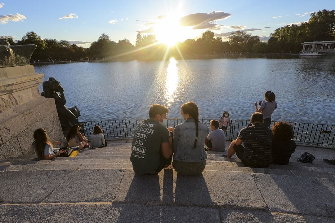 Una pareja conversa con las mascarillas puestas en el parque del Retiro de Madrid