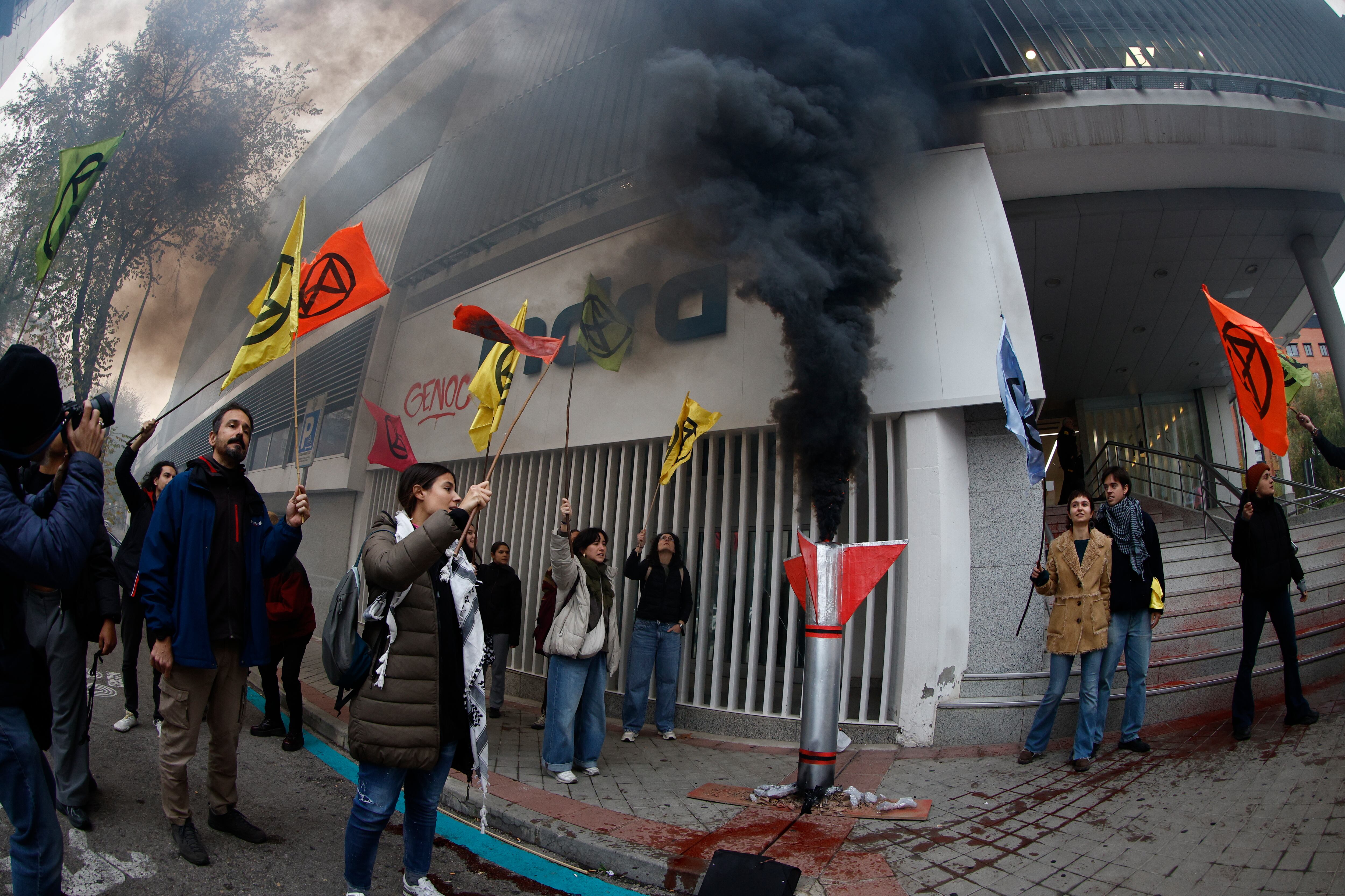 MADRID, 17/11/2025.- Activistas del grupo Rebelión o Extinción protestan este lunes ante la sede de Indra en Madrid, en el marco de la celebración de la cumbre COP30 en Brasil, para denunciar la deriva militarista y exigir al gobierno español que destine recursos a políticas climáticas y sociales en vez de a la industria militar. EFE/Rodrigo Jiménez
