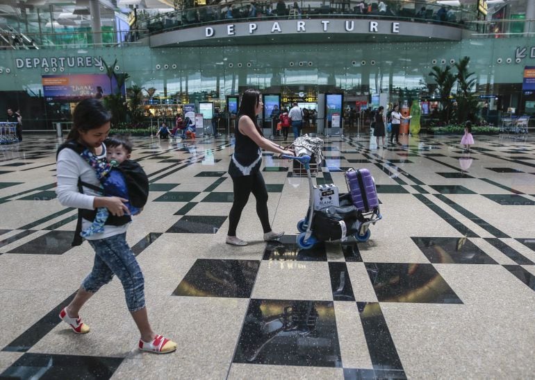 Un grupo de personas buscan las puertas de embarque en el aeropuerto de Singapur. 