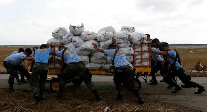 Miembros de la policía empujan un carro con suministros de socorro en la base militar de Tacloban