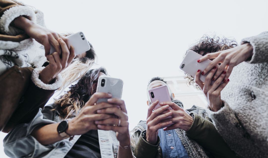 Un grupo de amigos utilizando su teléfono móvil.