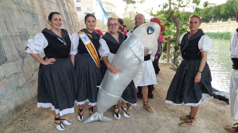 Miembros del grupo de Coros y Danzas El Pinar de la peña El Caldero de San Pedro del Pinatar sostienen a la sardina a su llegada a los Molinos del Río