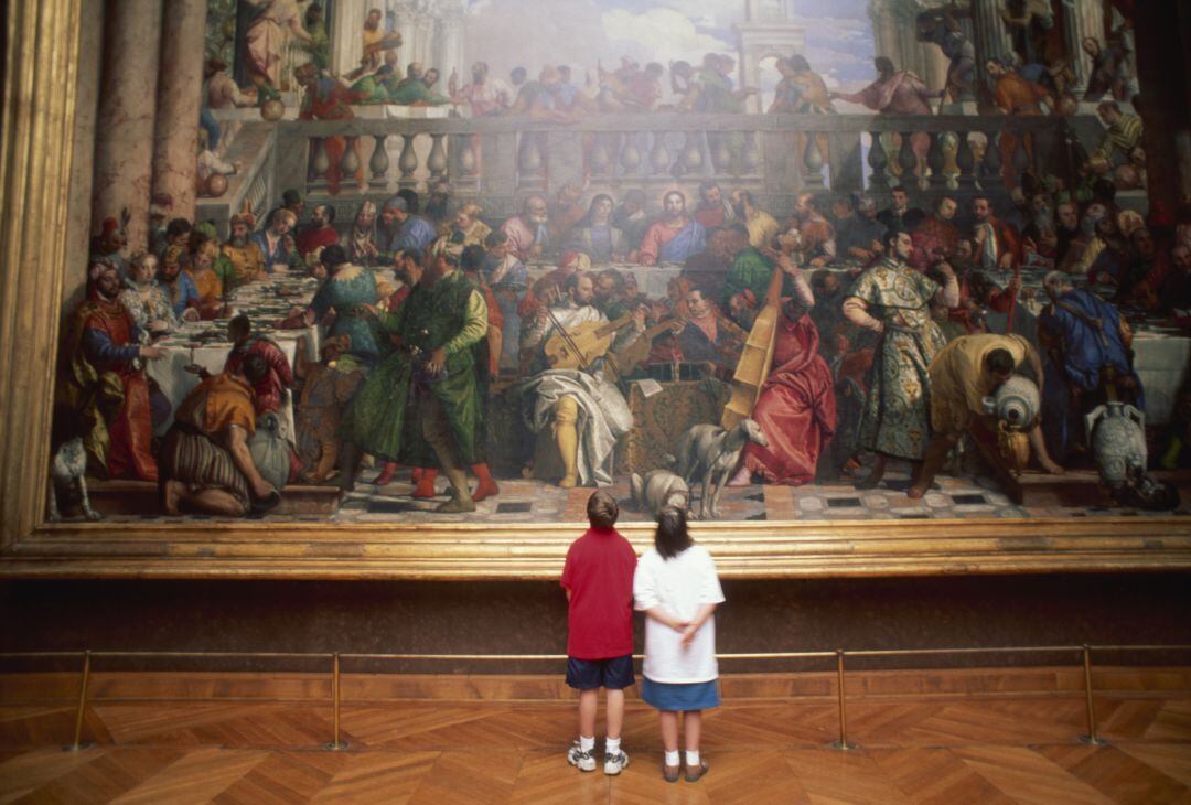 Dos niños observan un cuadro en una galería.