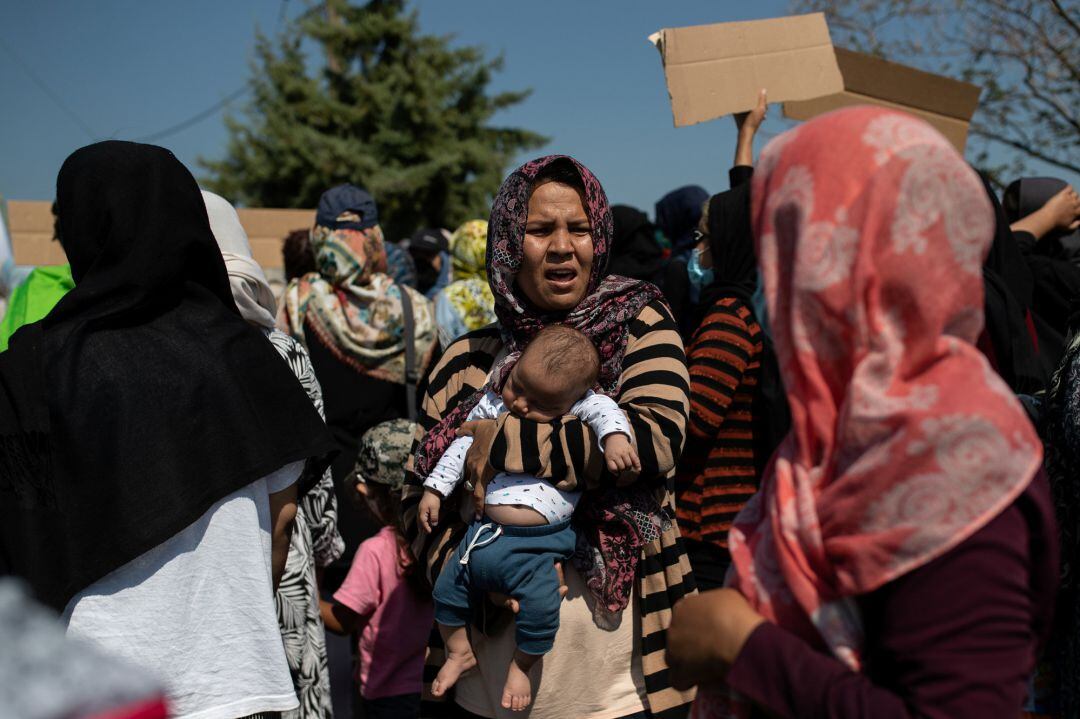 A woman holds a baby as refugees and migrants from the destroyed Moria camp protest near a new temporary camp, on the island of Lesbos, Greece, September 14, 2020