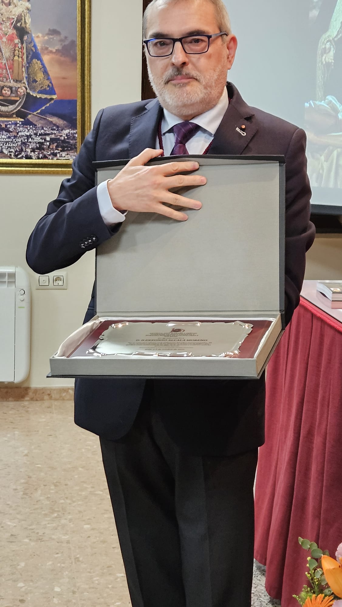 El autor del libro sobre la historia del Santo Entierro, Ildefonso Alcalá, muestra la placa conmemorativa