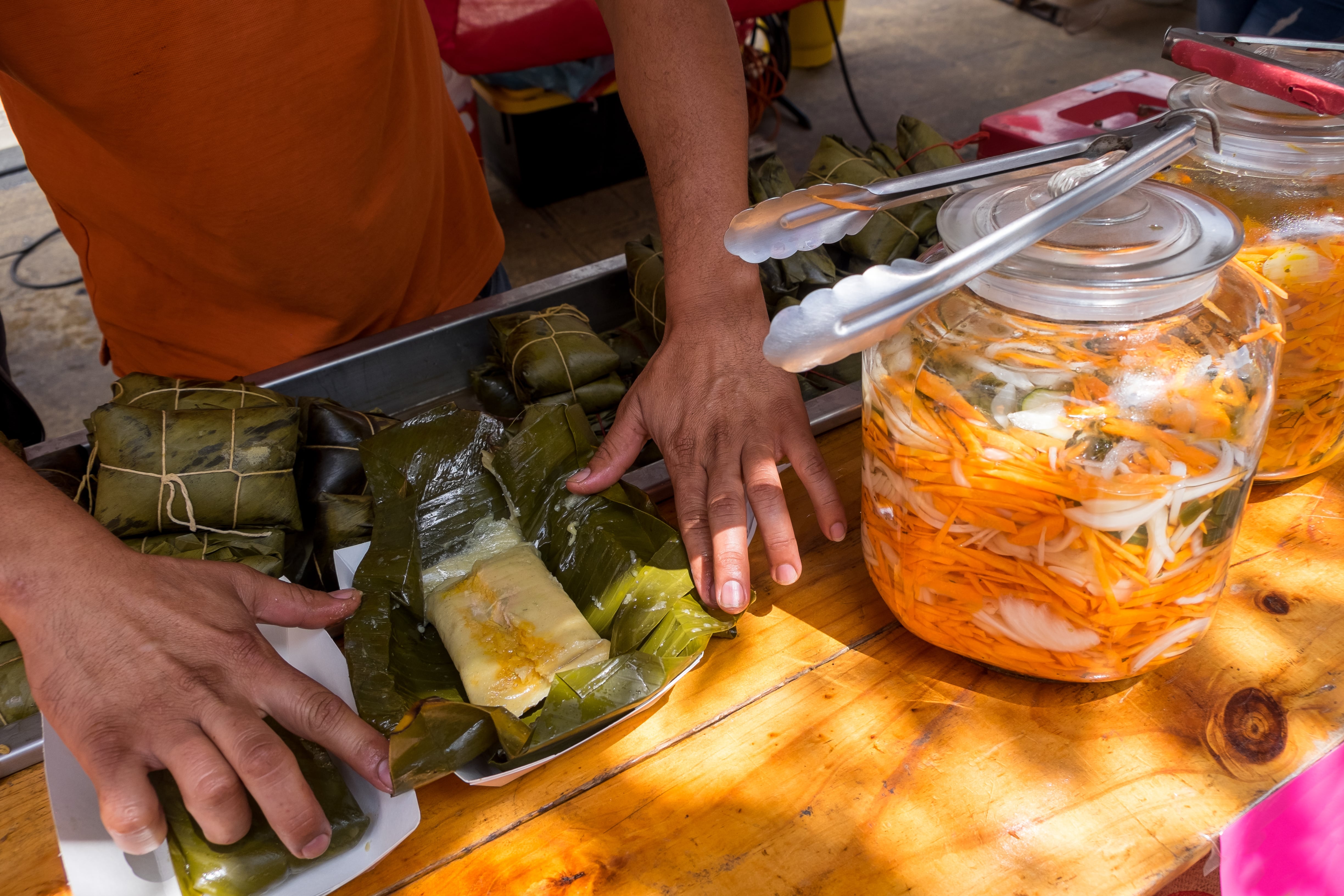 Un hombre prepara los tradicionales tamales envueltos en hoja de plátano.