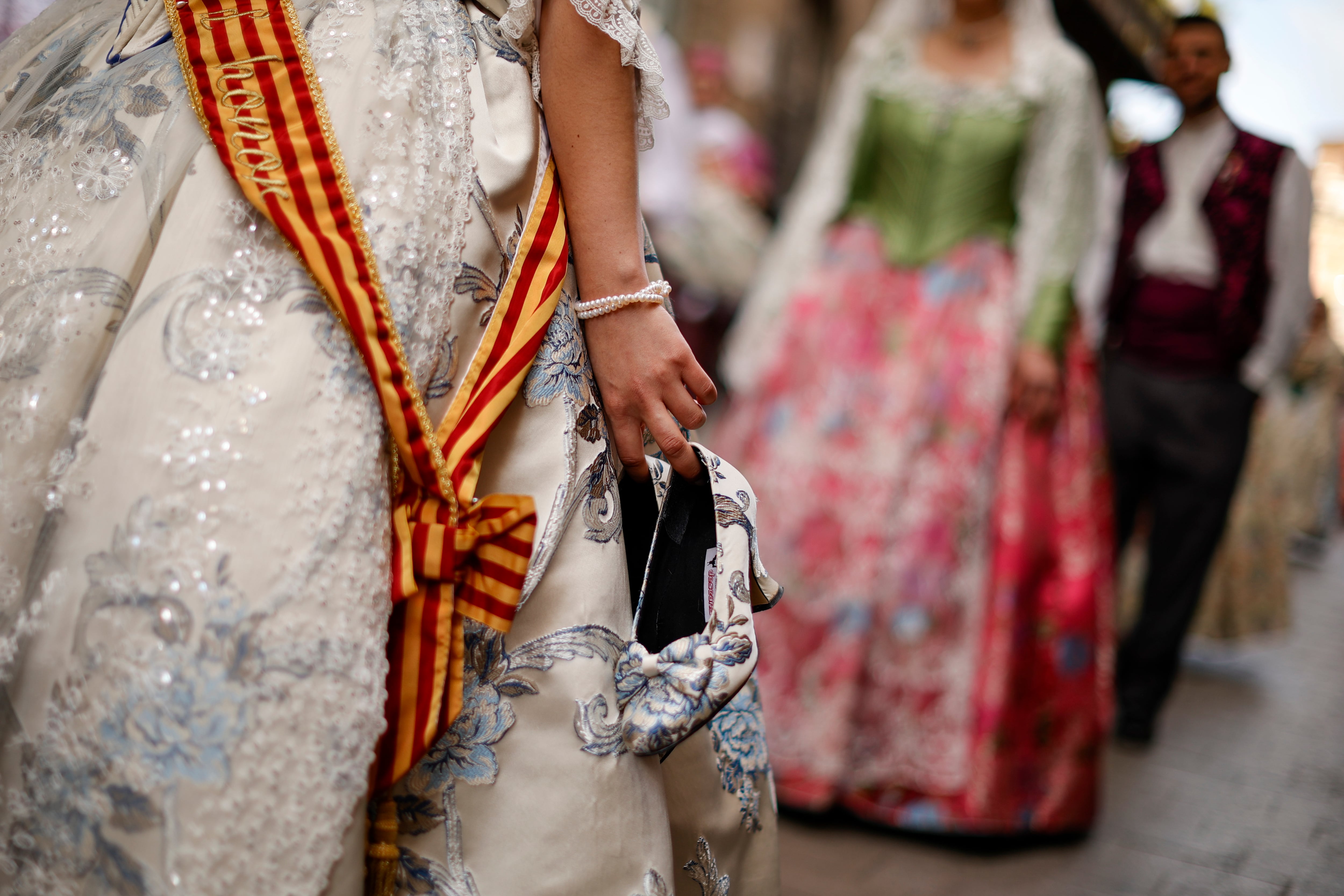 Una fallera lleva sus zapatos en la mano mientras desfila en la ofrenda floral de las Fallas que recorre València este viernes y el sábado hacia la plaza de la Virgen para depositar, ante el catafalco de madera de 15 metros de altura ubicado entre la Basílica y la Catedral, sus ramos y pedir la bendición de su patrona.