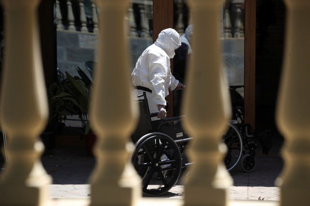 Un trabajador introduce una silla de ruedas en una residencia de Mayores 