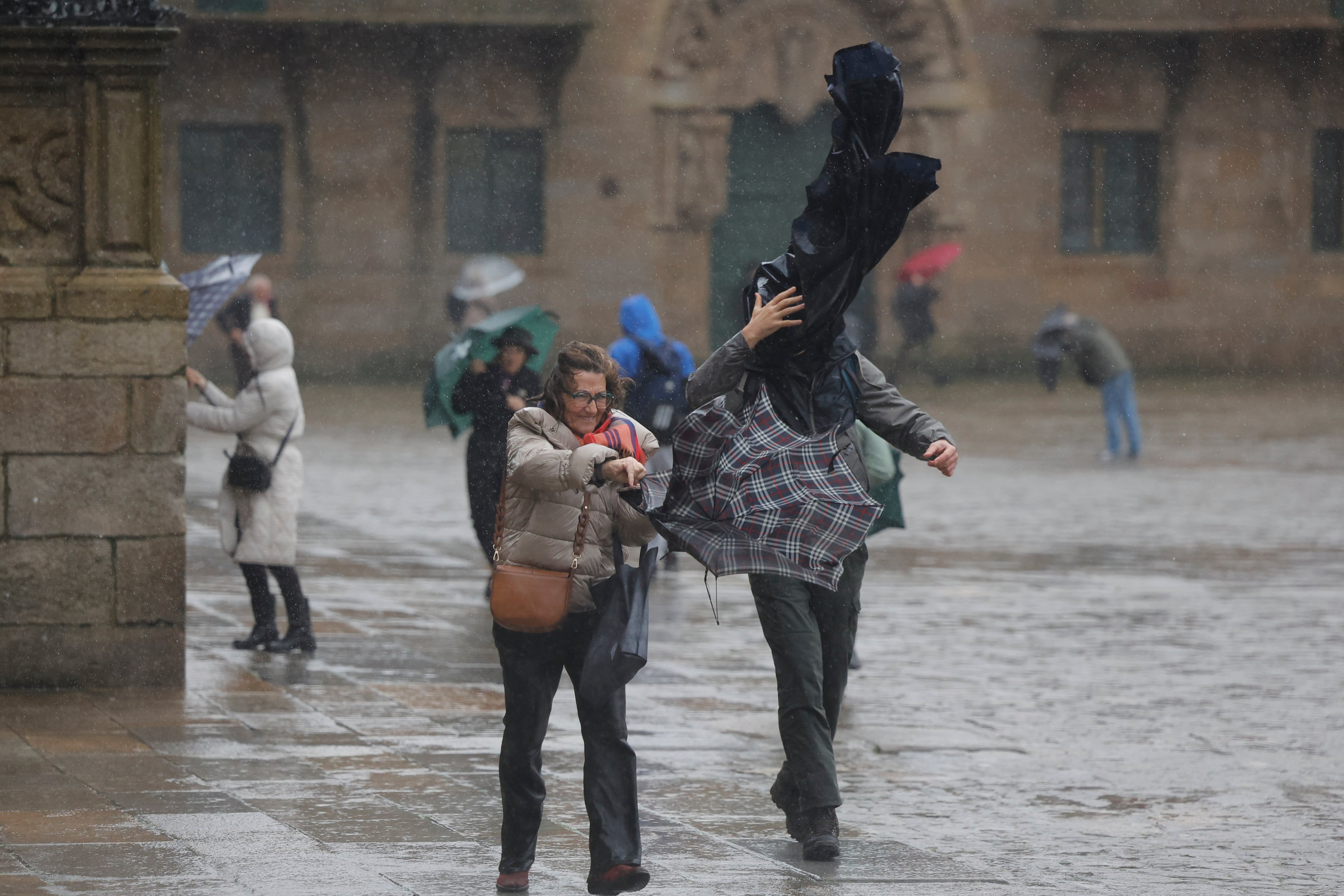 Turistas hoy domingo en la plaza del Obradoiro en Santiago de Compostela. Un potente temporal asociado a la borrasca Herminia va a azotar con fuerza a la península, con lluvias muy intensas y generalizadas, viento con rachas huracanadas por encima de los 20 kilómetros por hora en algunos puntos y aviso rojo en Galicia, donde las olas pueden alcanzar 10 metros de altura hoy en Santiago de Compostela. EFE/Lavandeira jr.