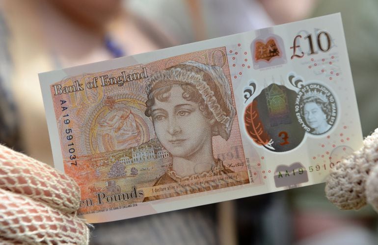 Una mujer ataviada con un traje de la época posa con el nuevo billete de diez libras con el rostro de Jane Austen.