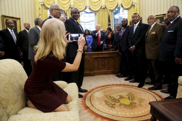 Kellyanne Conway (i), toma una fotografía arrodillada en el sofá.