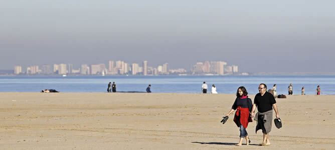 Una pareja pasea disfrutando del sol y las temperaturas suaves en la playa de La Malvarrosa de Valencia.