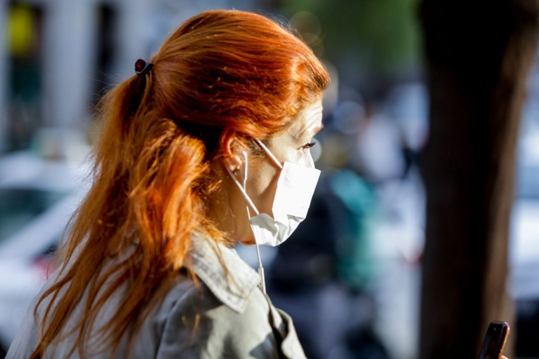 Una mujer pasea con una mascarilla.