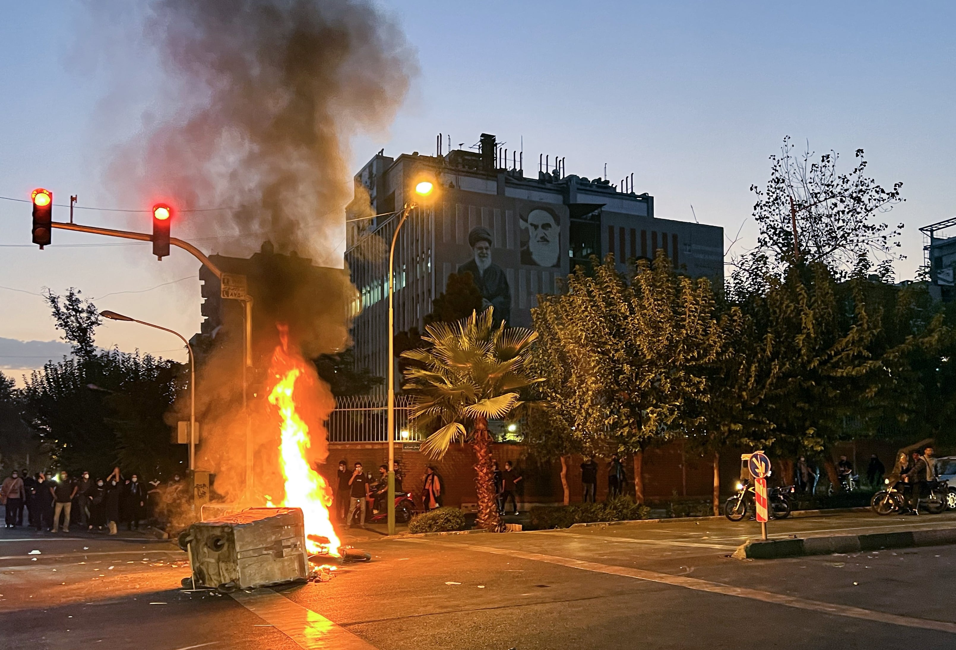 Protestas en las calles de Teherán por la muerte de Mahsa Amini ante un edificio con la imagen del líder supremo de Irán, Ali Jameneí