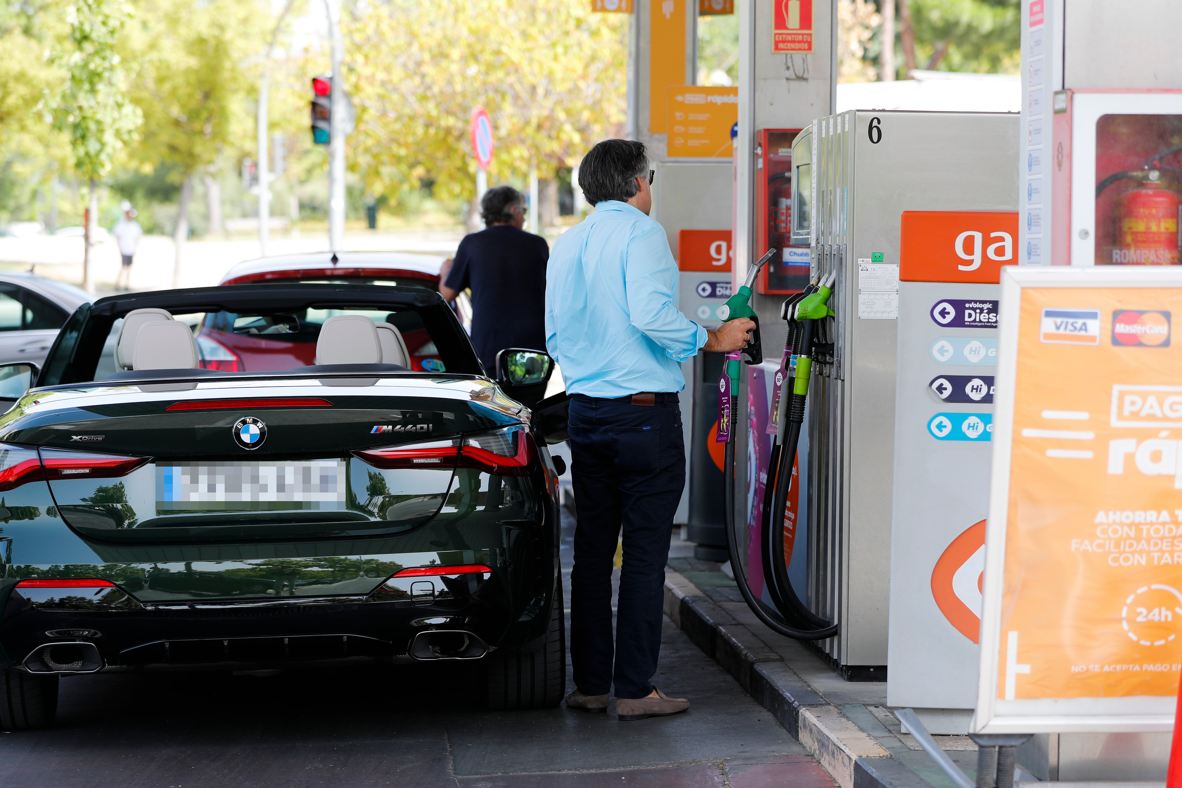 Unas personas repostan combustible en una gasolinera de Madrid