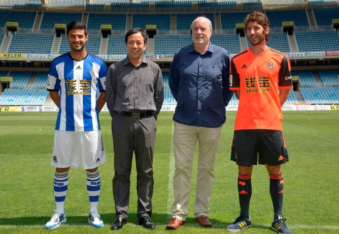 Los jugadores Carlos Vela y Esteban Granero, flanquean a Li Qunfenfg, asistente de la empresa china y Ángel Oyarzun, vicepresidente del club, en la sesión fotográfica en Anoeta con el nuevo patrocinador.