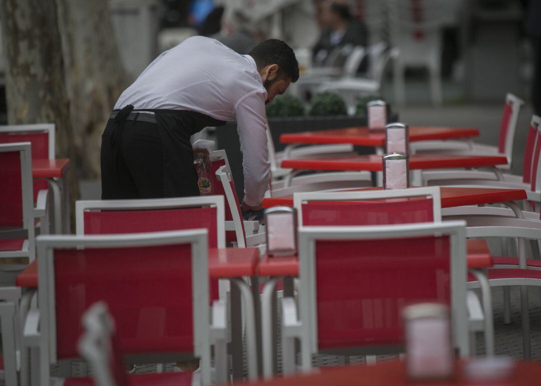 Un camarero limpia las mesas de una terraza.